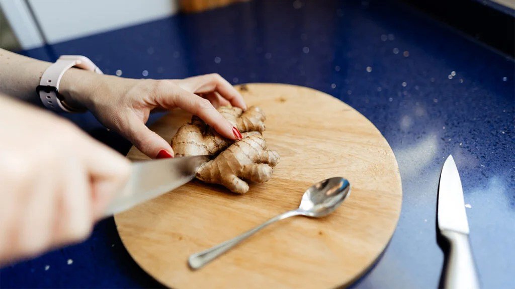 A person chopping up ginger, a herb that may support thyroid function.
