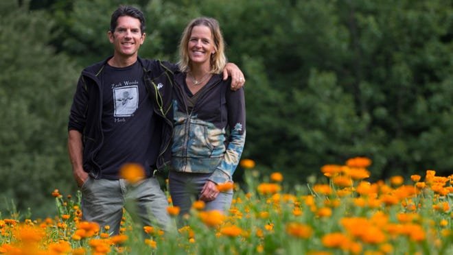 Melanie and Jeff Carpenter of Zack Woods Herb Farm stand surrounded by Calendula blooming in their fields in Hyde Park. The couple farm 10 acres of organic herbs and sell largely to wholesale accounts.