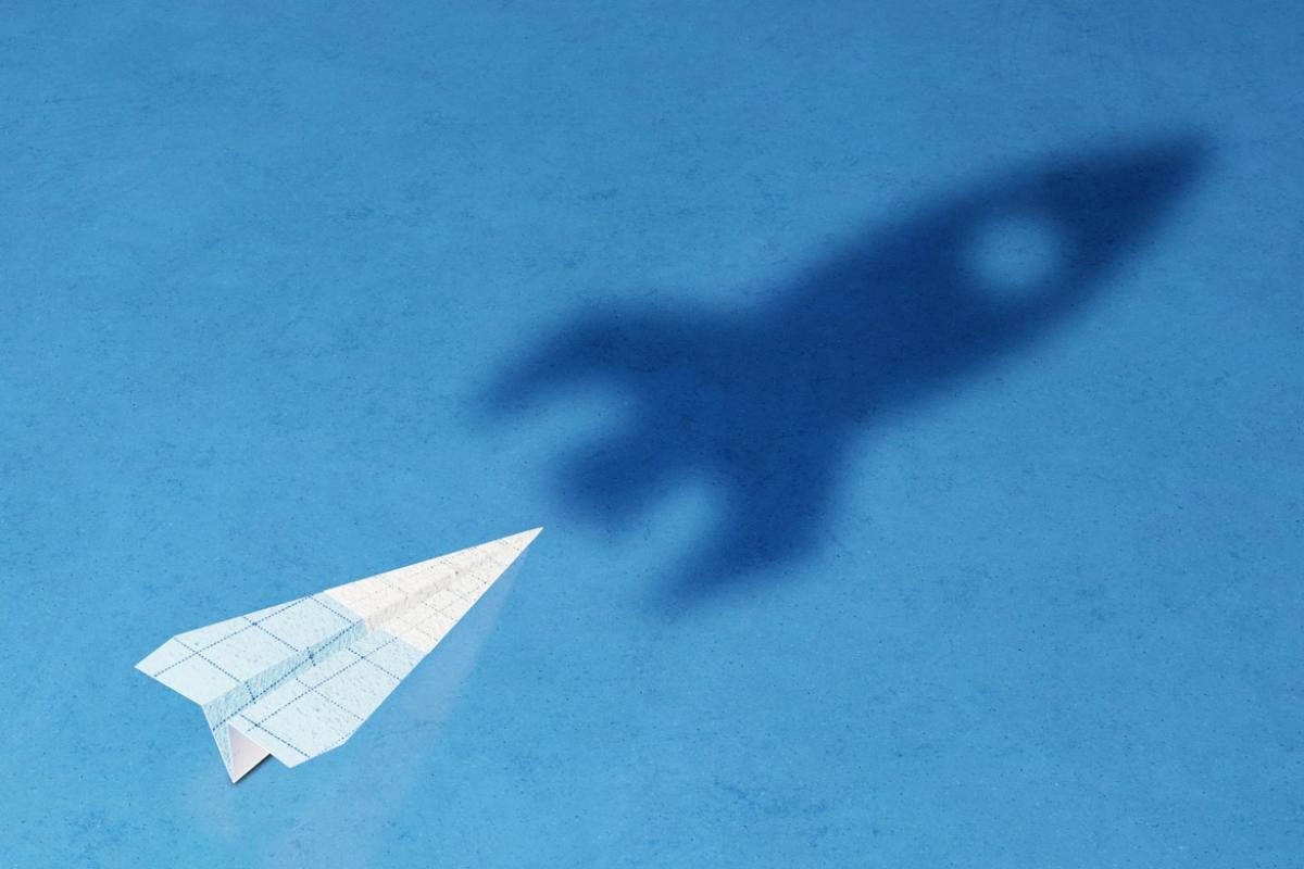 Paper airplane in the shadow of a rocket