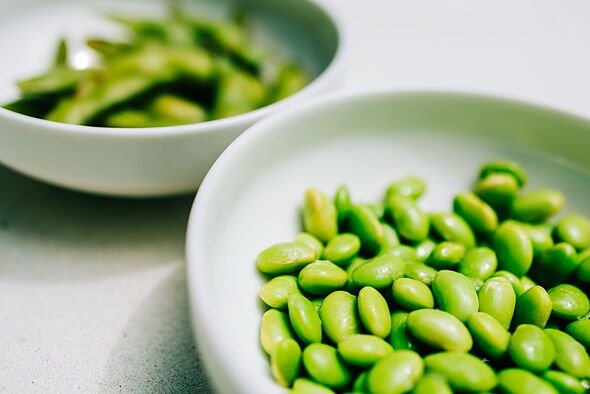 Edamame beans and pods in white bowls on light background